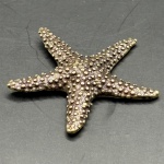 Miniatura representando estrela-do-mar, feito em cobre, rico em detalhes. Medidas: Altura 1,5 cm x Largura 4 cm x Profundidade 4 cm.