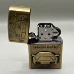 COLECIONISMO - Isqueiro recarregável em metal dourado com figura de uma Lamborghini Murcielago em relevo. Medindo 5,5 x 3,2 x 1,3 cm.
