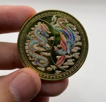 Moeda decorativa representando Fênix e Dragão Chinês em metal dourado com case de acrílico. Diâmetro: 4 cm. Espessura: 3 cm.