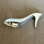Abridor de garrafa em formato de sapato de salto, feito em metal, medindo 4,5 cm x 11 cm.