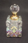 Perfumeiro em vidro furta-cor e detalhe em metal dourado, trabalhado em relevo, no interior possui um pequeno palito em vidro para uso do perfume. Medindo 6,5 cm de altura.