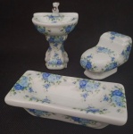 COLECIONISMO - Três miniaturas em porcelana representando peças para banheiro decoradas com rosas na cor azul. Perfeitas. medindo a banheira 10 x 5 x 3 cm, a pia  10 x 6 x 4.5 cm e o vaso sanitário 7 x 6 x 4 cm.