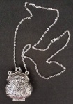 Colar com pendente de bolsinha em metal prateado , trabalhado em relevo representando arabescos. A peça abre e fecha e possui um imã. Medindo 5 x 4 cm a bolsinha .