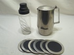 Jogo de jarra em aço inox, coqueteleira em vidro e 6 descansos de copo em aço inox.Medindo 10cm x 18,5cm de altura.