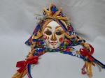 Máscara decorativa para pendurar em gesso decorado com policromia e acabamento em tecido, peça européia. Medindo 36cm de comprimento x 17cm de altura.