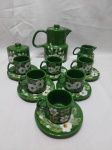Jogo de servir café com 9 peças em porcelana verde pintada à mão com flores brancas provavelmente Weiss. Composto de bule, leiteira, açucareiro e 6 xícaras com pires. Leve bicado em um pires.