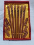 Jogo de 6 pares de hashi com descanso em madeira com imagem de dragão. Medindo o hashi 24cm de comprimento.