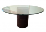 Mesa redonda com base revestida de couro e espesso tampo de vidro com bordas bisotadas. Medida 130cm de diâmetro do tampo.  Lote deve ser retirado na Barra da Tijuca mediante agendamento prévio.