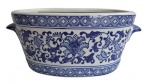 Grande floreira em porcelana, na forma oval, ricamente policromada de azul e branco, exaltando florais e guirlandas. Medidas 39x20x16cm.