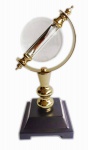 Belíssimo e elegante objeto decorativo em metal dourado, esfera em vidro e base em material sintético preto. Medida 12x27cm.