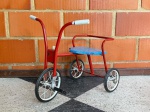 COLECIONISMO - VINTAGE - Velocípede em ferro tubular pintado de vermelho, assento em chapa de metal pintado de azul. Manufatura Bandeirante. Década de 60. Alt. 48cm.