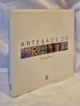 Livro Artesãos do Brasil medindo 24 cm por 24 cm.