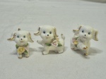 Jogo de 3 enfeites de cachorro em porcelana com flores em alto relevo. Medindo o maior 5cm de altura.