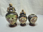 Jogo de 3 potiches em porcelana oriental com pintura de gueixa, sendo um sem tampa. Medindo o maior 11cm de bojo x 22cm de altura.