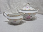 Sopeira e molheira em porcelana Steatita floral com friso ouro. Medindo a sopeira 19cm x 12cm de altura, tampa com fio de cabelo na pega. Com leve desgaste no friso.