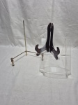 Lote de 3 suportes para prato de mesa, sendo em acrílico, metal e madeira. Medindo o maior 26,5cm de altura.