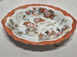 Travessa oval funda em porcelana oriental com pintura de gueixas, aves e paisagens. Medindo 29cm x 22cm x 4,5cm de altura.