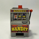 COLECIONISMO - MÁQUINA DE DIVERSÃO `JACKPOT BANDIT`, Em miniatura - funcionando. Utiliza 02 (duas) Pilhas do tipo AA para ascender luz vermelha do topo. Funciona inclusive sem as pilhas. Marca Radica. Mede aprox. 17 cm de altura contado com o giroflex superior.