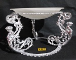 Belíssima centro de mesa/fruteira em bronze decorada com ninfas, arabescos e folhas de acanto, três pés, base interna em murano (adaptado). Altura: 25 cm - Diâmetro: 35 cm.