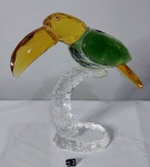 Escultura em cristal, representando "Tucano sobre Galho" nas cores verde, amarelo e translúcido. Medidas: 23x21cm.