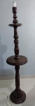 Luminária de pé alto em madeira esculpida no formato de tocheiro, ornamentado por segmentos com profundos entalhes, folhagens e anelado. Coluna reta interrompida à meia altura por plateau circular liso. Base circular rematada por lindos entalhes. Medindo 1,50 metros.