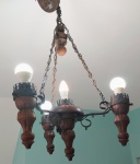 Antigo e suntuoso lustre para 4 luzes, em metal e madeira no formato de lampião. Sustentado por 3 correntes. Laterais com trabalho vazado. Braços torneados. Med.: 88x47 cm.