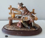 Belíssima estatueta em resina italiana representando um andarilho morador de rua lanchando no banco da praça, com base em madeira, ricamente detalhado, medindo 19cm de altura por 14cmX 28cm de base.