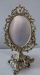 Espelho de mesa executado em pesado bronze profusamente adornado ao estilo Vitoriano, com presença de volutas, buquês de flores, acantos e concheados. Medindo 32cm x 19cm.