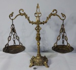 Balança decorativa executada em bronze, ganchos arqueados, sustentados por fuste representando figura feminina, bandejas suspensas por correntes. Med.: Alt. x Comp. cm.