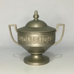 Antigo açucareiro em metal cinzelado , decorado com faixa estilizada. Marcas de desgastes. Dimensões: 14 cm x 17 cm x 7 cm.