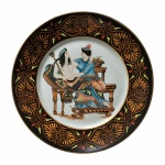 Belo Medalhão de porcelana esmaltada  com cena Grega  ao centro e faixa decorada com arabescos nas cores laranja, amarelo, vermelho sobre fundo preto. Dimensões 29 cm de diâmetro.