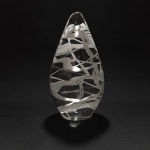 MURANO - ESCULTURA DECORATIVA EM  NO FORMATO GOTA, COM DETALHES RODEADO POR LINHAS BRANCAS, MEDINDO 21X14CM