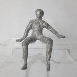 Estatueta figurativa em metal prateado. Dimensões: 19 cm x 15 cm.