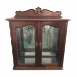 Bela Cristaleira em madeira nobre com vidros bisotados, duas portas, interior com 2 prateleiras de vidro e fundo espelhado (presença de manchas do tempo). Possui chave. Parte superior decorado com florão talhado à mão. Dimensões: 120 cm x 100 cm x 50 cm. Retirada no bairro de Cascadura.