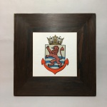 Belo azulejo com pintura de brazão fixado em placa de madeira. Lateral com desgastes. Dimensões: 2,5 cm x 28 cm x 28 cm .