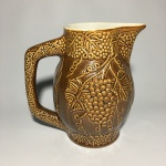 Antiga Jarra em cerâmica esmaltada na core caramelo ricamente decorada com cachos de uvas e cena galante. Dimensões: 19,5 cm x 12 cm x 19 cm.