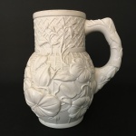 Antiga caneca de origem portuguesa em porcelana, decorada com arranjos florais. Apresenta trinca na parte superior. Dimensões: 17 cm x 14 cm x 11 cm.