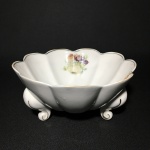 Antiga saladeira trípode com borda ondulada, decorada com figuras de frutase filetes pintados à ouro. Dimensões: 9 cm x 20 cm.