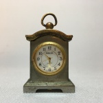 Delicado relógio de mesa em miniatura de metal, funcionando. Dimensões: 5,5 cm x 3,5 cm x 2 cm.