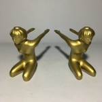 Par de escultura em metal revestido de dourado. Dimensões: 13 cm x 15 cm x 7 cm / 2,5 kg.