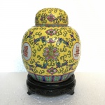 CHINA - Belo potiche em porcelana esmaltada decorado com arabescos e elementos vegetalistas sobre fundo amarelo. Acompanha penhanha em madeira. Dimensões: 18 cm x 12 cm.