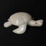 Tartaruga esculpida em pedra na cor branca. Dimensões: 4 cm x 10 cm x 13 cm.
