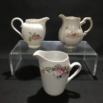 Conjunto com 3 leiteiras pequenas em porcelana nacional.Sinais de desgastes. Dimensões: 11 cm altura maior peça.