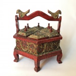 Antiga caixa haxagonal em madeira decorada com arabescos pedras coloridas e alça ostentando pássaros. Exemplar possivelmente do sudeste asiático. Possui 6 tampas. Falta uma pega. Presença de desgastes. Dimensões: 23 cm x 21 cm x 23 cm.