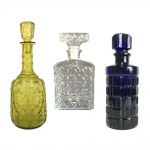 Parte de coleção com três antigas garrafas de vidro translúcido, amarelo e azul. Garrafa azul com discreto bicado. Dimensões: 31 cm x 12 cm (maior peça).