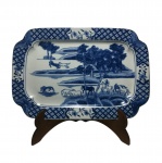 Travessa oriental em porcelana esmaltada decorada com cena do campo em tons de azul pintada à mão. Exemplar com assinatura no fundo. Dimensões: 31 cm x 21 cm.