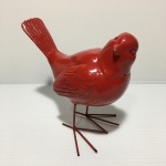 Pássaro na cor vermelho feito de material sintético com patas de metal. Dimensões: 13 cm altura.