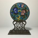CHINA - Adorno de mesa em bronze fenestrado com placa circular cloisonné, decorada com flores. Dimensões: 16 cm.