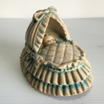 COIMBA - PORTUGAL - Antiga estatueta de bebê no berço em cerâmica policromada (apresenta sinais de desgastes). Dimensões: 8 cm altura.