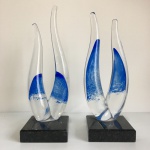Murano - Par de esculturas em vidro repuxado com detalhes internos na cor azul sobre base em granito preto. Dimensões: 23 cm altura.